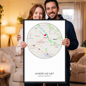 Framed personalized Where We Met map print — a custom Boise, Idaho street map in a circle with a red heart marker, the couple's names, place and date, in a black wooden frame.