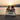Two people sitting on a dock at sunset, wrapped in a personalized blanket with a cassette tape design.