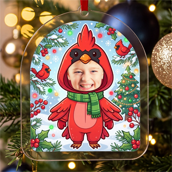 Personalized cardinal Christmas photo ornament — a real face on a cute cartoon red cardinal onesie in a snowy scene, on a red ribbon