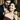 Man putting heart-shaped necklace on smiling woman in elegant dress during romantic evening