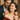 Man gifting silver pendant necklace to smiling woman in red off-shoulder dress during romantic celebration