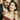 Smiling woman receiving gold pendant necklace from man during romantic celebration with champagne in the background