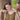 Mother placing necklace around smiling daughter's neck during heartfelt moment