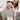Happy woman surprising her smiling partner with a wrapped gift box while covering his eyes on the couch